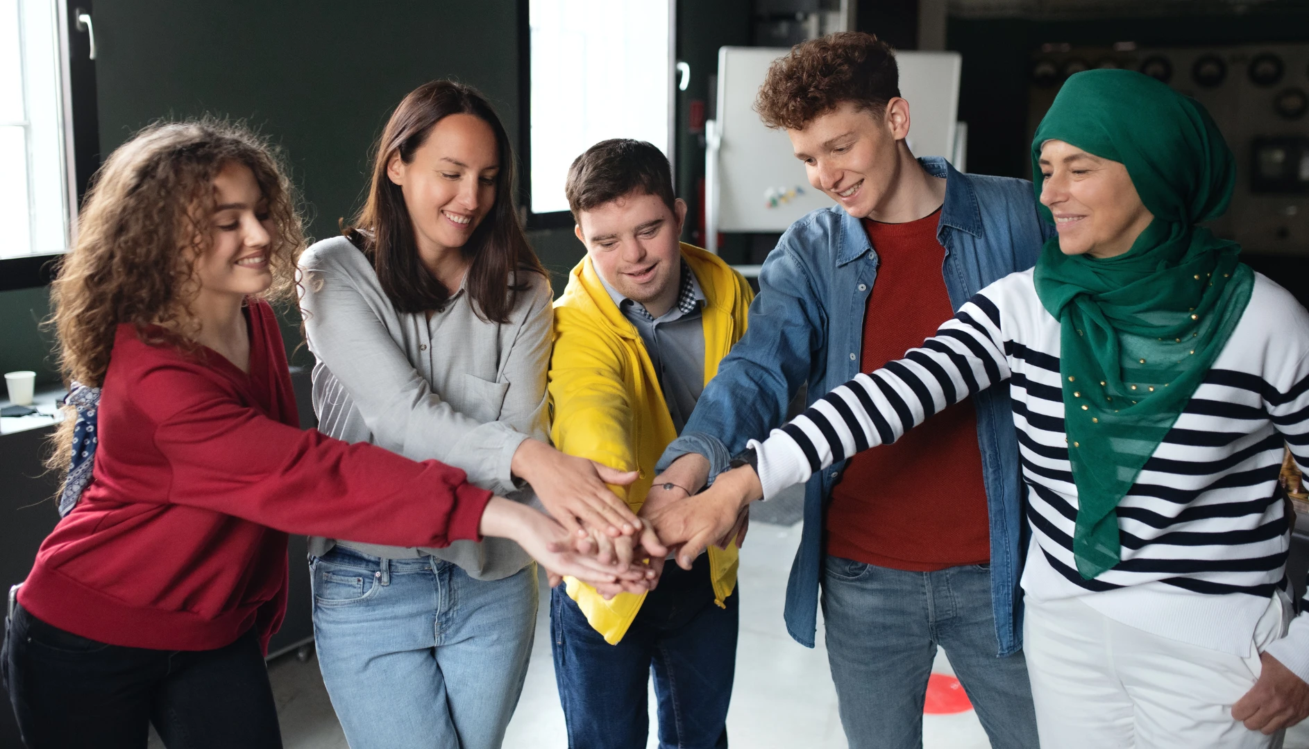 Group of young friends putting hands together